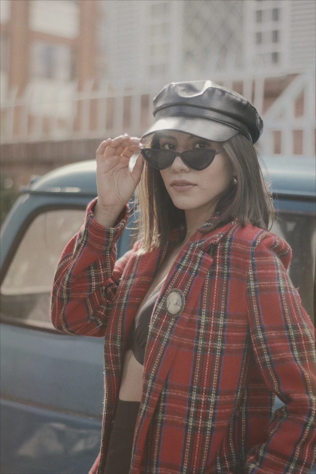 Millen Guerrero in a plaid coat and cap on a city street